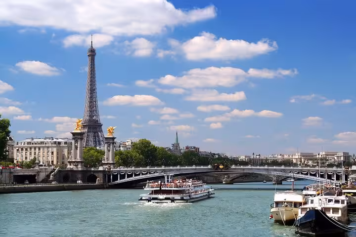Eiffel Tower and Seine River cruise boat in Paris, part of a private luxury tour with Louvre visit