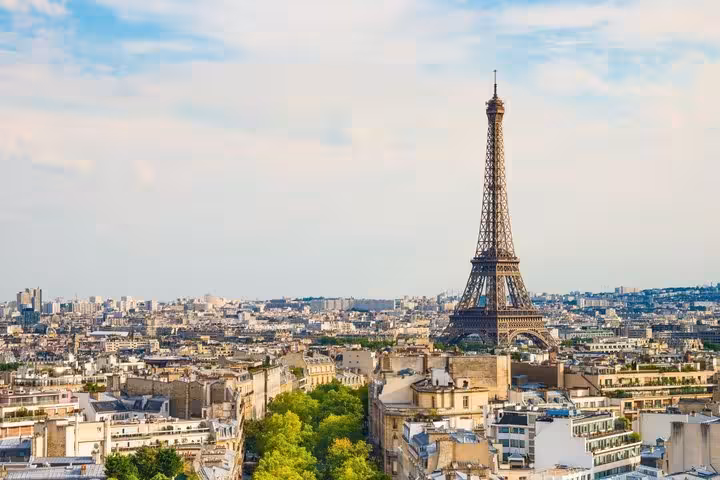Aerial view of Paris skyline with Eiffel Tower rising above Haussmann buildings on a sunny day