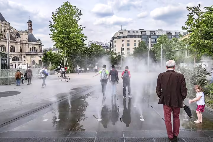 Families enjoying a playful day at a Paris fountain, perfect for kids, with historic architecture and greenery in the background.