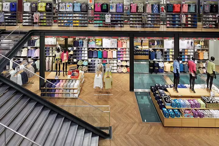 Colorful clothing displays on multiple floors of a bright retail fashion store with herringbone wood floors