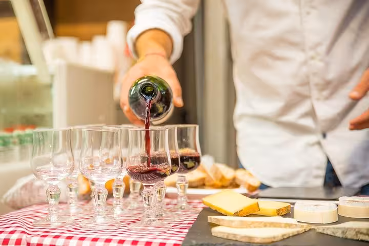 Wine being poured into glasses, paired with cheese on a Parisian food tour led by a French gastronomy expert.