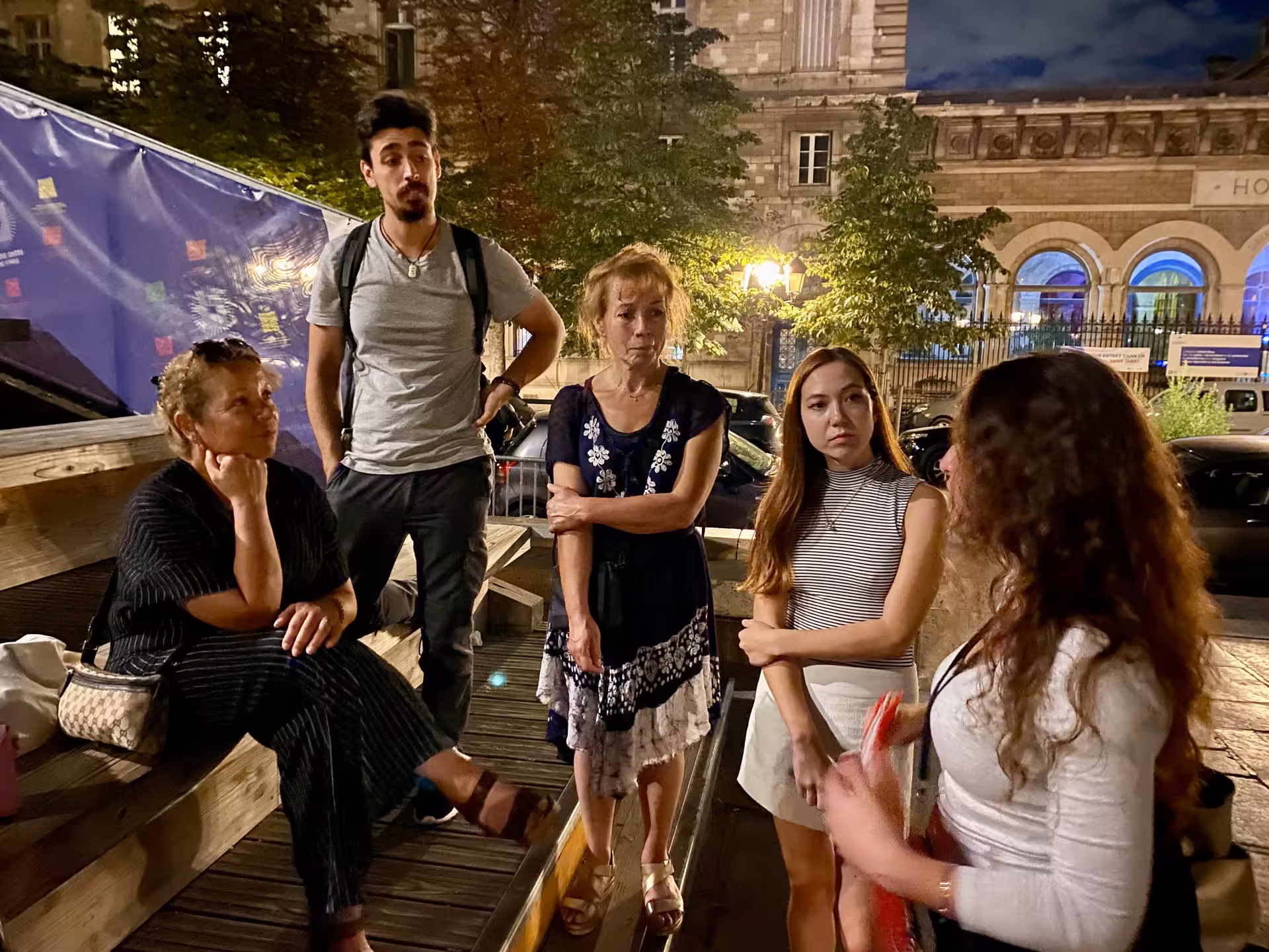 Tour group listens to guide in Paris, exploring key sites from the French Revolution at night.