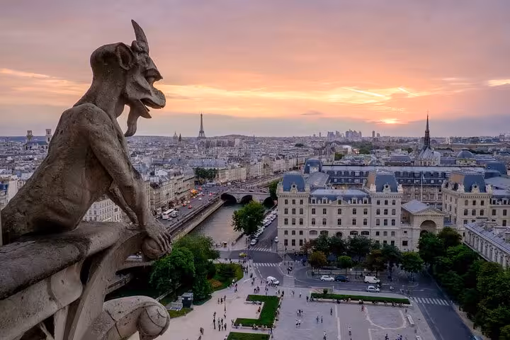 Gargoyle on Notre-Dame Cathedral overlooking Paris skyline with Eiffel Tower at sunset