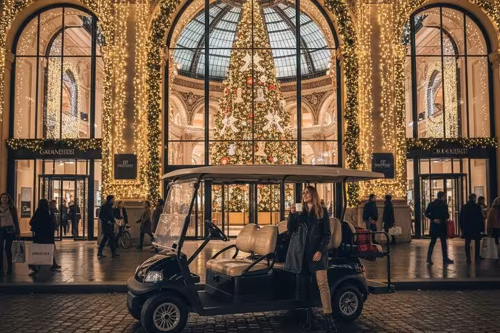 Woman beside golf cart in front of Christmas lights and tree at elegant Paris gallery