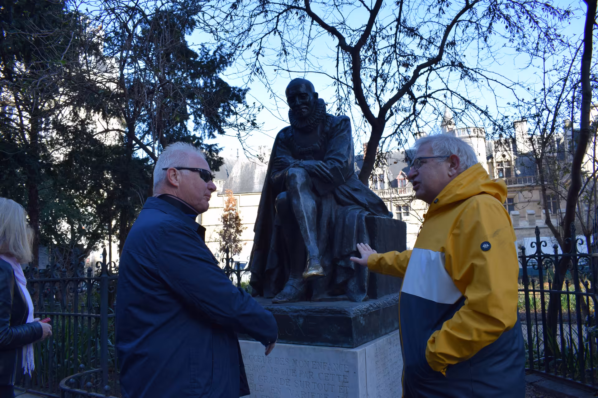 Two tourists discussing a bronze statue in a Paris park during a small group guided tour