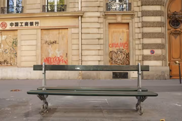 Green Paris bench in front of Haussmann facade, capturing Napoleon III era streets on Paris city tour