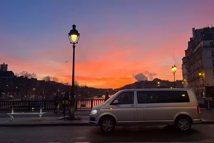 Guests posing by a minivan with the Eiffel Tower behind on Hop On Paris city highlights minivan tour