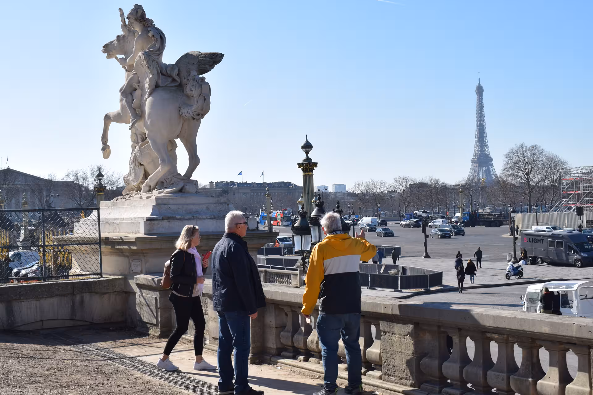 Tourists admiring the Eiffel Tower from Place de la Concorde next to a Pegasus sculpture in Paris