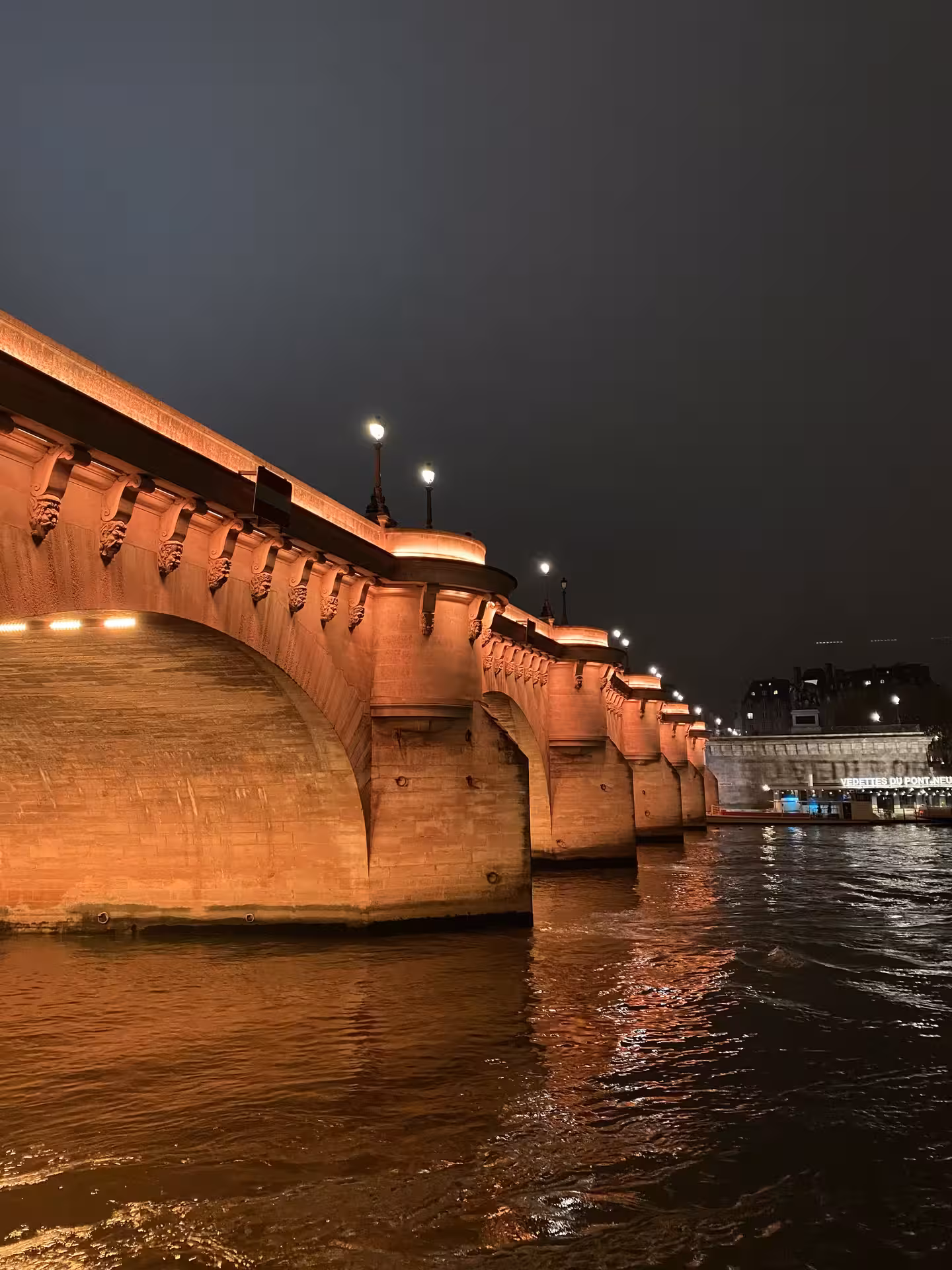 Close-up of a historic Paris bridge illuminated at night, showcasing a key site on the Justice and Crime Tour.