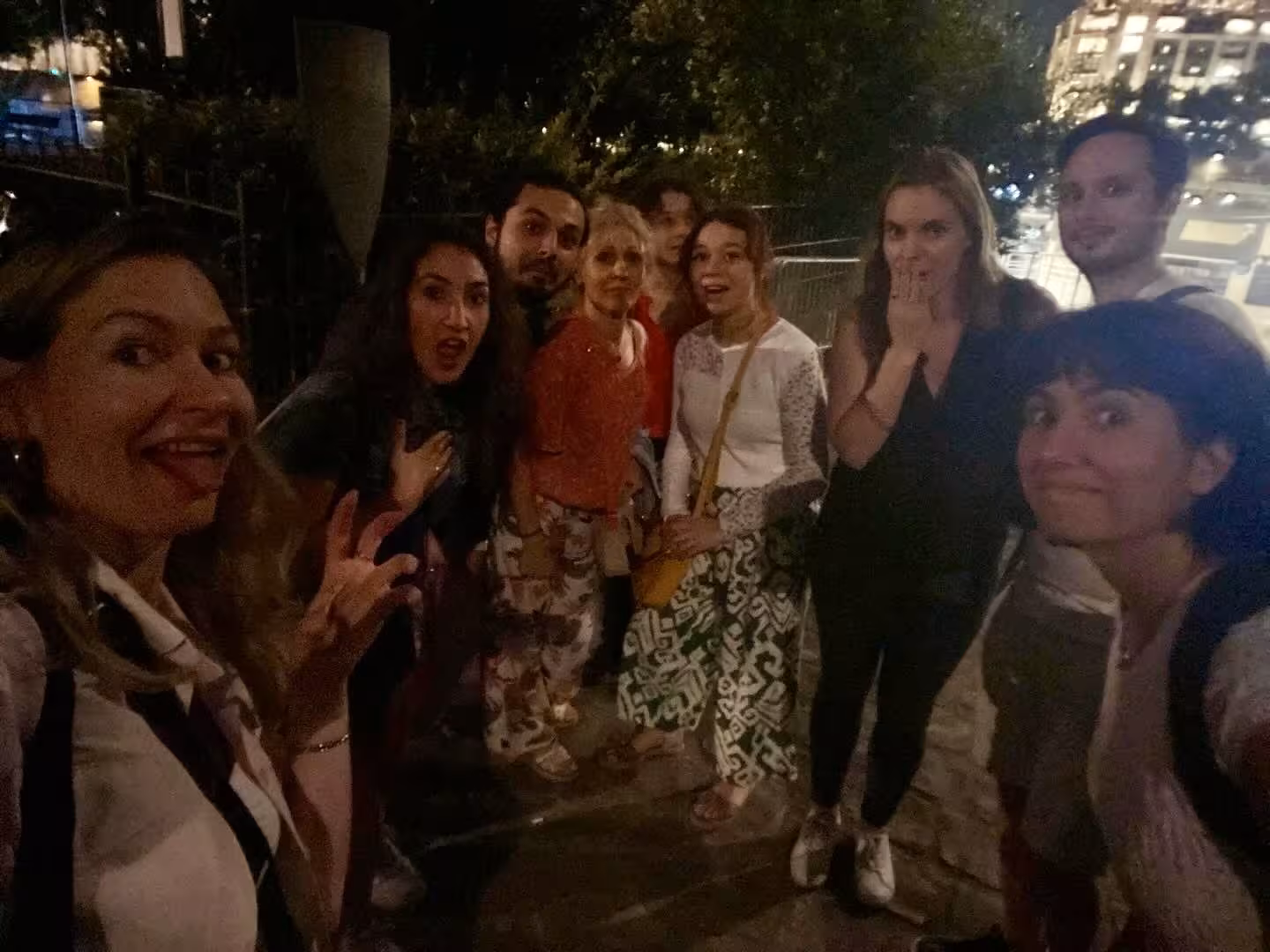 Enthusiastic group enjoying the Paris Justice and Crime Tour at night with city lights in the background.