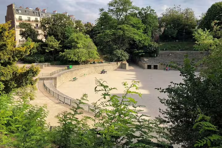 Ancient Roman amphitheater arena in Paris Latin Quarter surrounded by lush trees and Haussmann buildings