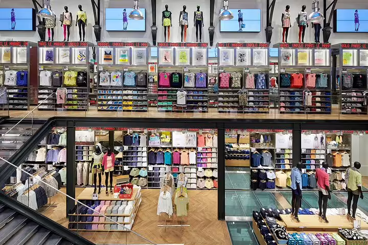 Colorful multi-level clothing store with mannequins displaying fashion items on shelves and racks