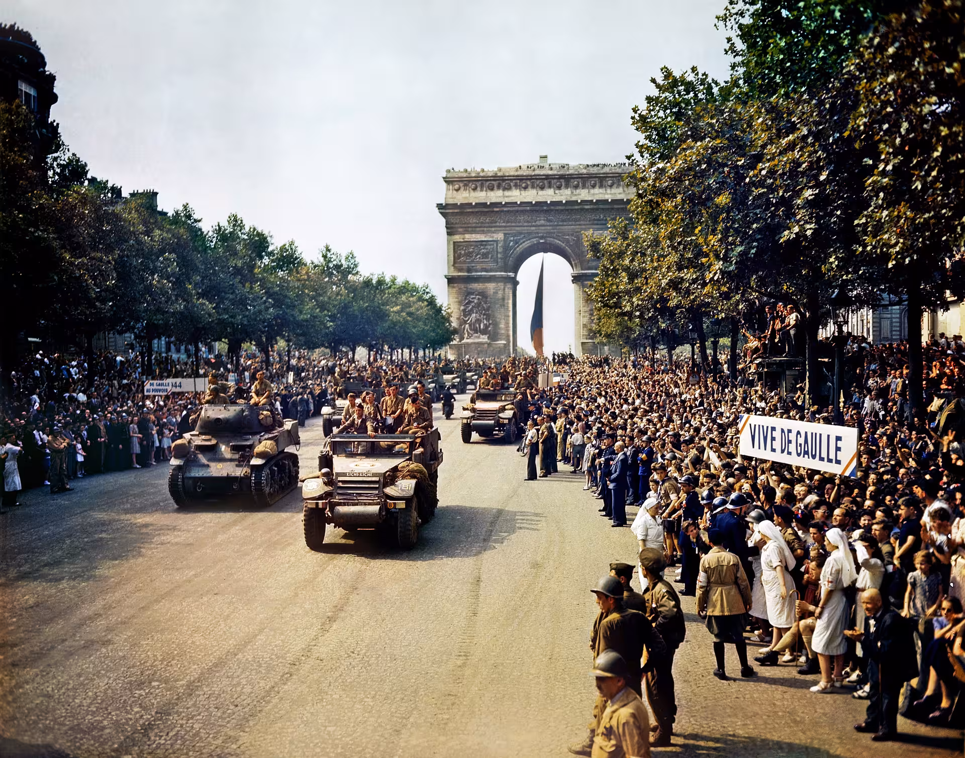 Allied military parade on Champs-Élysées with Arc de Triomphe, crowds holding Vive De Gaulle sign, Paris liberation 1944