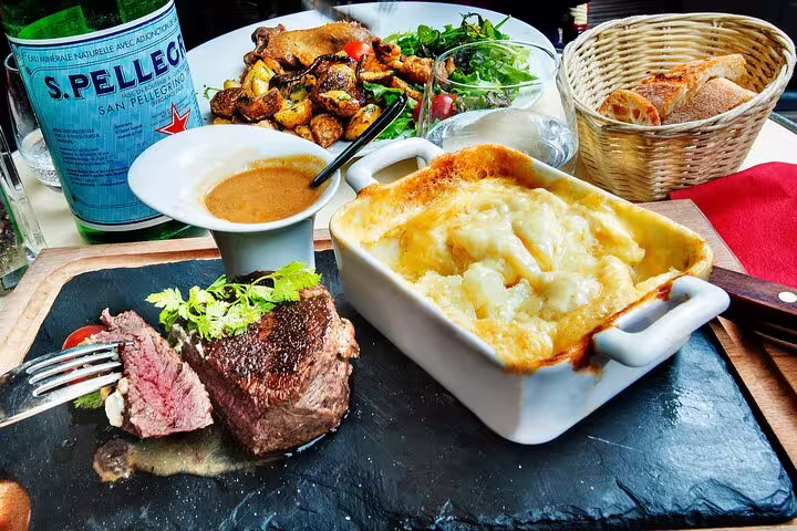 Gourmet French meal featuring steak, gratin, salad, and bread, perfect for your Parisian adventure on the Louvre and Sainte Chapelle tour.