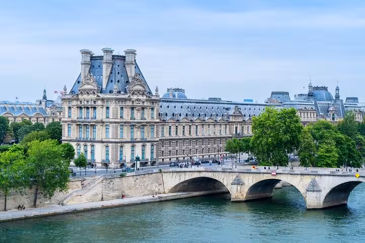 Seine River view of the Louvre Palace and bridge, seen on the unlimited hop-on hop-off Paris cruise pass