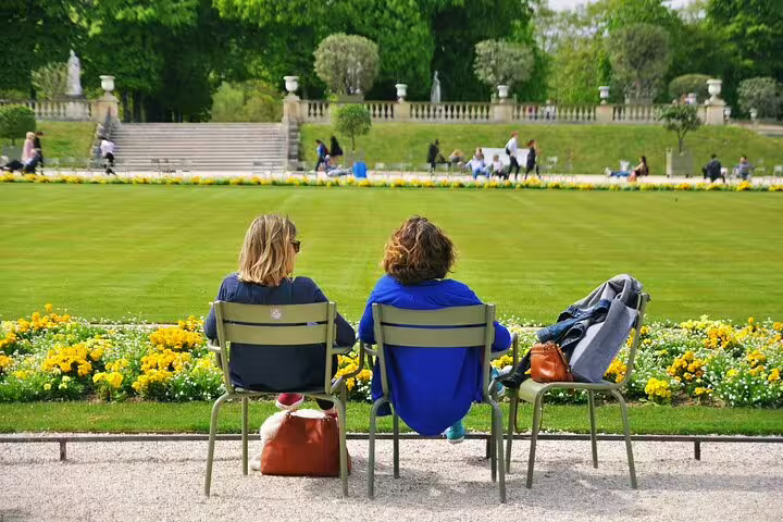 Two women relax in Paris's lush Luxembourg Gardens, enjoying the serene atmosphere and iconic French landscape.