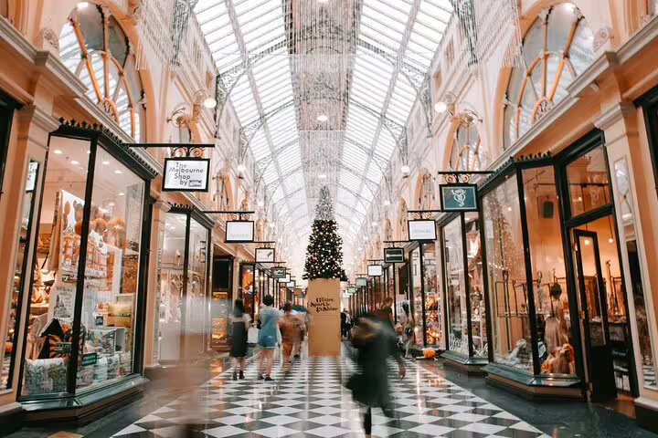 Elegant indoor shopping arcade with glass ceiling, Christmas tree, and shoppers walking on checkered floor