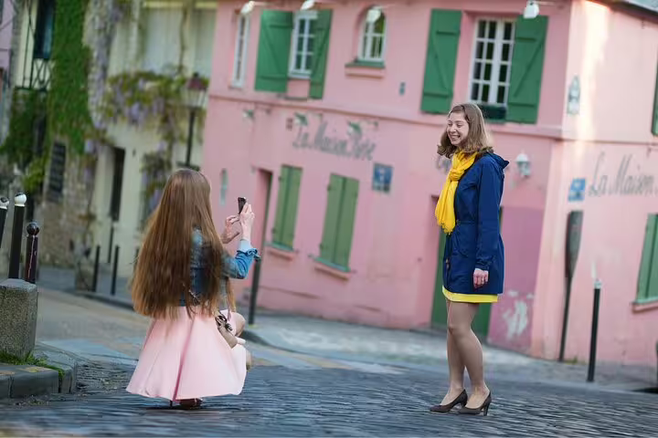 Two women enjoy a photoshoot on a charming street in Montmartre, capturing the vibrant essence of a Paris full-day tour.