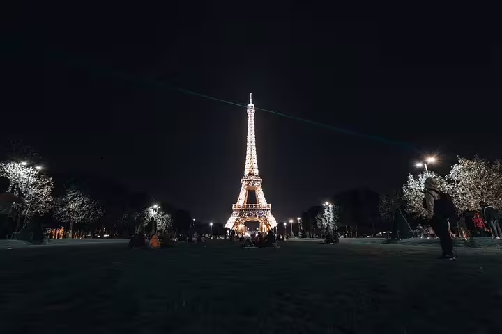 Eiffel Tower illuminated at night with golden lights, viewed from Champ de Mars in Paris