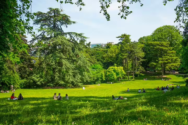People relaxing on green lawn in a lush Paris park on a sunny day