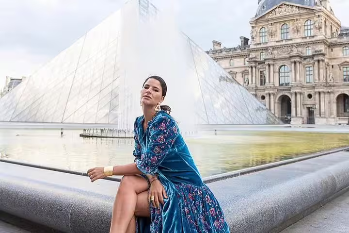 Woman in blue floral dress posing by Louvre Pyramid fountain during Paris private photoshoot