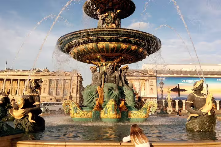 A visitor admires the ornate Fontaine des Mers at Place de la Concorde during a sunny Parisian day on a private tour.