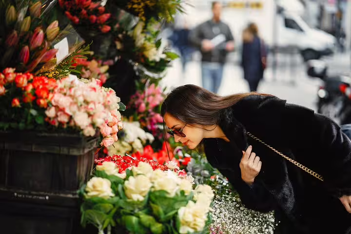 Woman admiring vibrant flowers at a Parisian market, showcasing the charm of a Paris private tour with Louvre entry and French crepes.