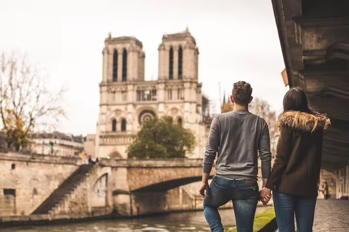 Couple enjoying a scenic view of Notre-Dame Cathedral on a Paris private tour with skip-the-line Louvre tickets and French crepes.
