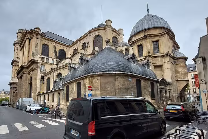 Black Mercedes van private transfer service near historic Paris church with domed architecture