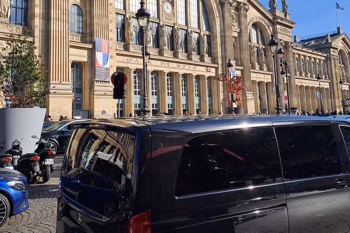 Black Mercedes private transfer van parked outside Gare du Nord train station in Paris