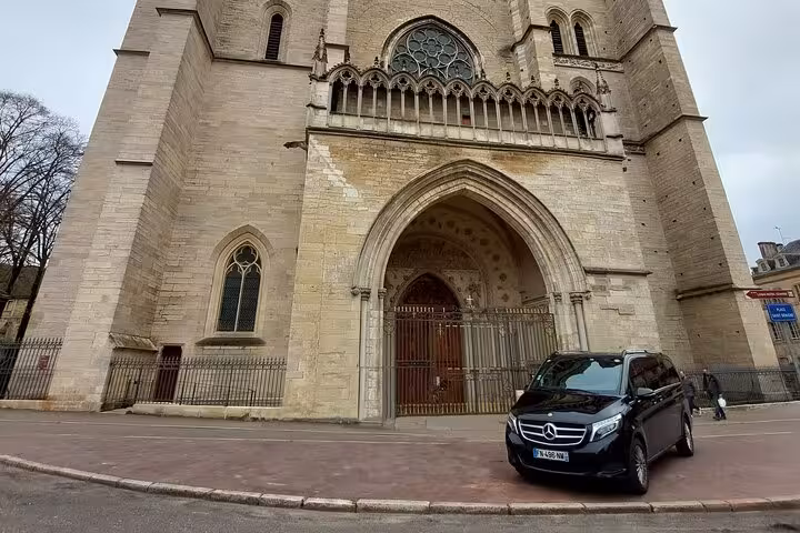 Black Mercedes V-Class van parked in front of a Gothic cathedral in Paris, France