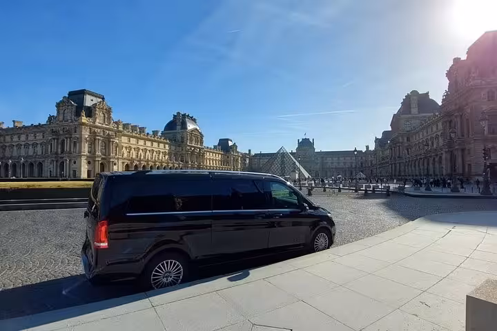 Black Mercedes van private transfer service parked at the Louvre Museum pyramid in Paris