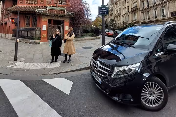 Black Mercedes private transfer van parked near two women on a Paris street corner