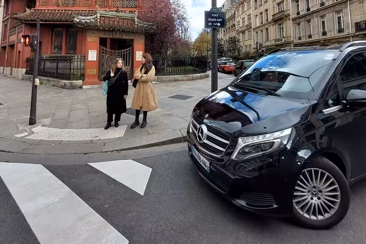 Black Mercedes-Benz private transfer van at Paris street corner with two passengers waiting