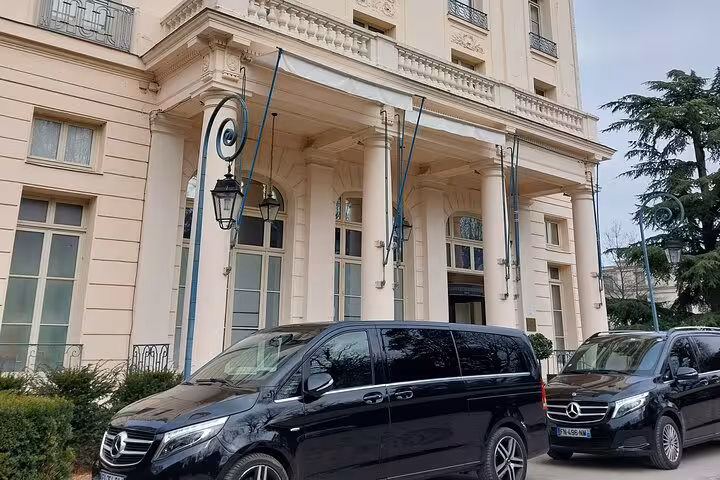 Two black Mercedes vans parked outside a grand Parisian hotel entrance with classical architecture