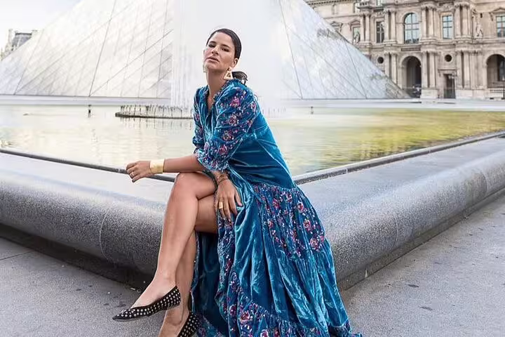 Woman in teal floral dress posing by Louvre pyramid fountain in Paris professional photoshoot