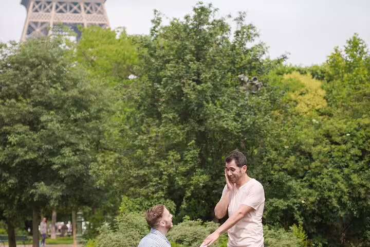 Man on one knee proposing to partner near Eiffel Tower in Paris park