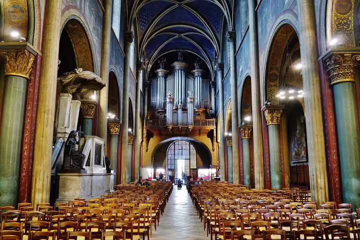 Ornate interior of a Paris church with pipe organ, vaulted ceilings, and rows of wooden chairs