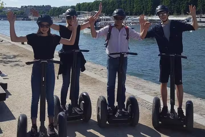 Group waving on Segways along the Seine riverbank, Paris Segway tour experience with included Seine River cruise
