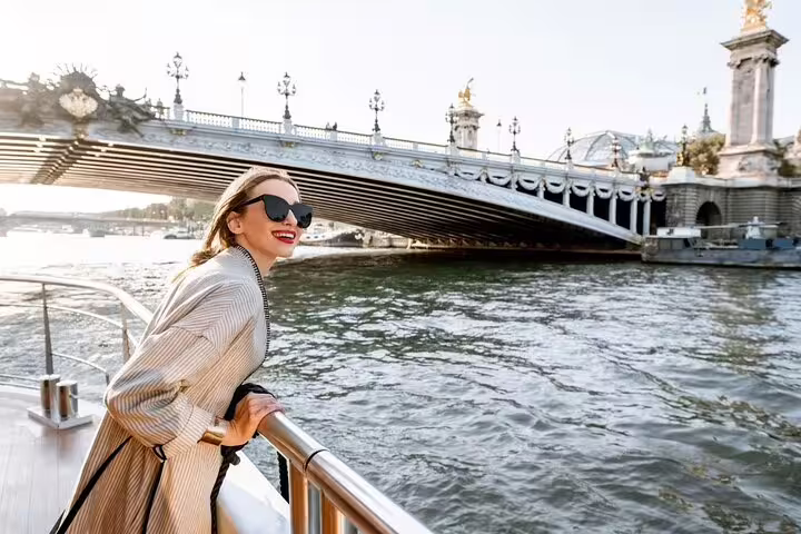 Smiling traveler on Seine sightseeing cruise passing ornate Pont Alexandre III bridge on a Paris insider city tour