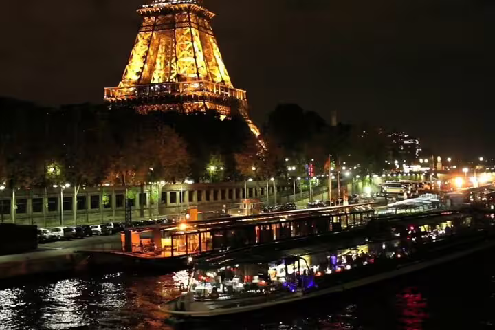 Eiffel Tower illuminated at night with a Seine River dinner cruise boat in Paris
