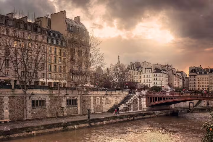 Seine River banks with Haussmann buildings and bridge in Paris at dramatic sunset