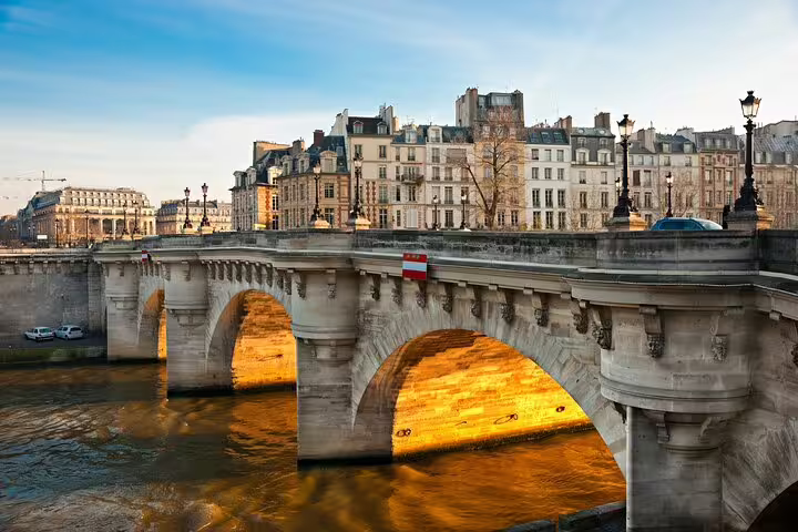 Historic stone bridge over the Seine River in Paris with classic Haussmann buildings in background