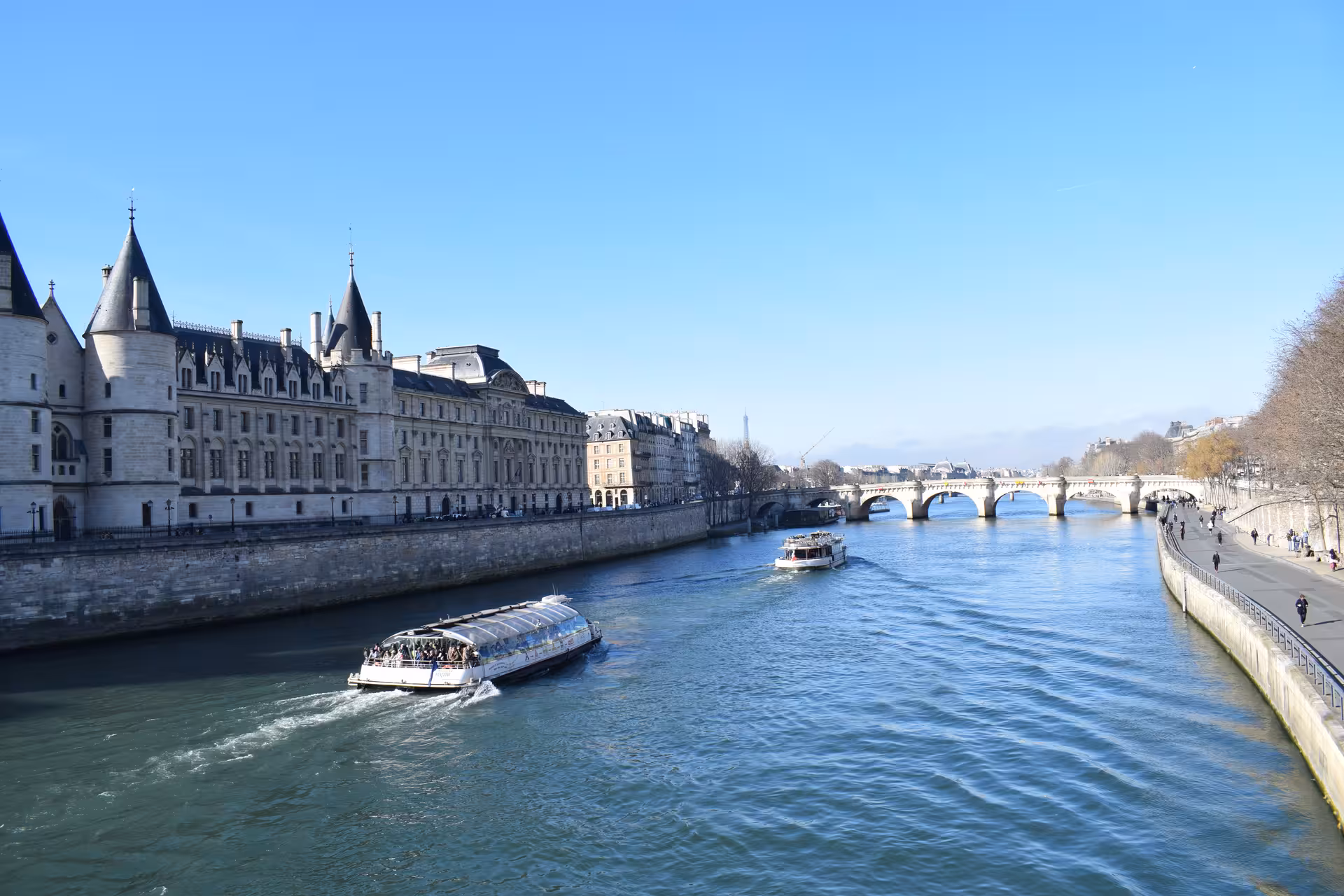 Bateaux Mouches river cruise on the Seine with the Conciergerie and Eiffel Tower visible in Paris
