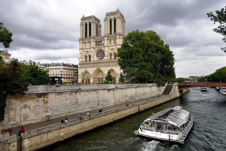 Scenic view of a Seine River cruise boat passing Notre-Dame Cathedral, perfect for a Paris airport layover tour experience.