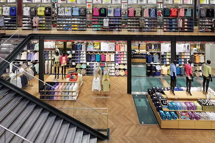 Multi-level colorful clothing store interior with mannequins and folded apparel displays