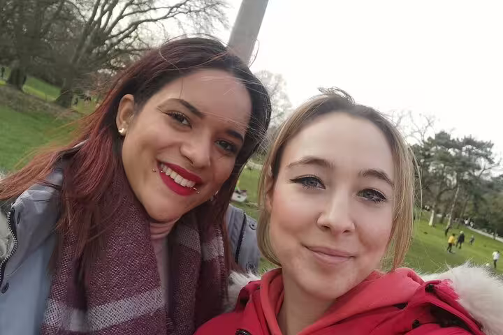 Two smiling women taking a selfie in a green park in Paris