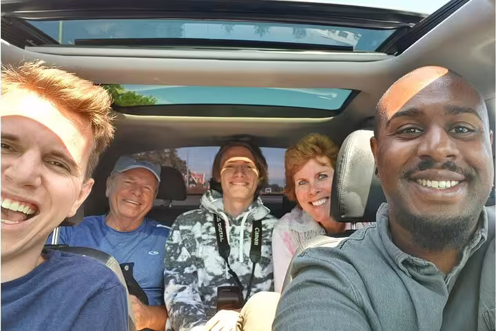 Happy group riding in private chauffeured car for Paris to Versailles two-way transfer with door-to-door pickup