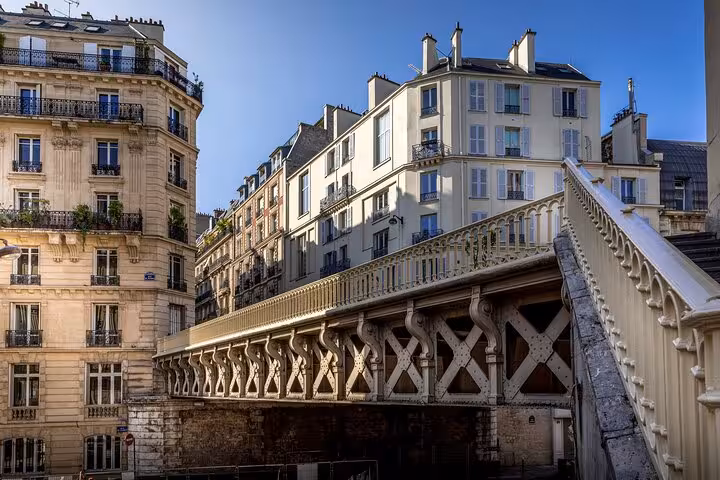 Ornate white iron bridge between classic Haussmann buildings in Paris neighbourhood