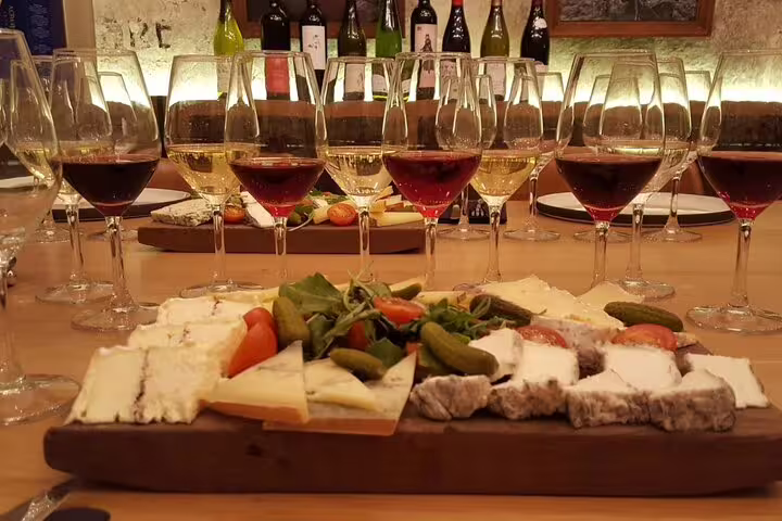 Wine and cheese tasting board with multiple glasses of red and white wine in Paris cellar